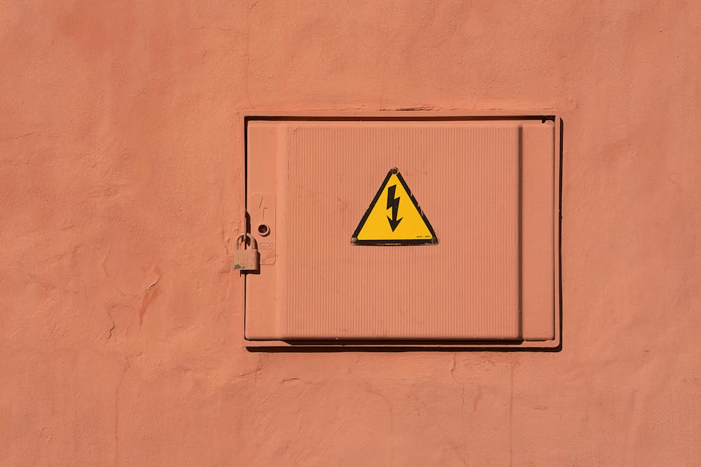 Bright yellow high voltage warning sign on a locked electrical box.
