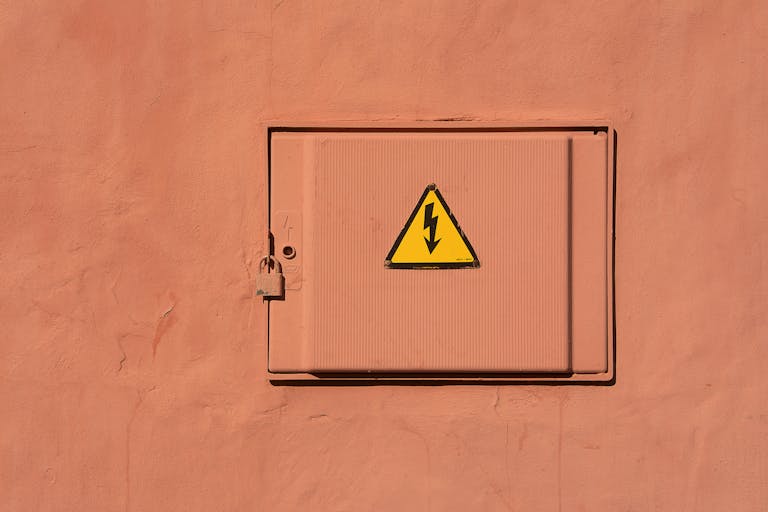 Bright yellow high voltage warning sign on a locked electrical box.
