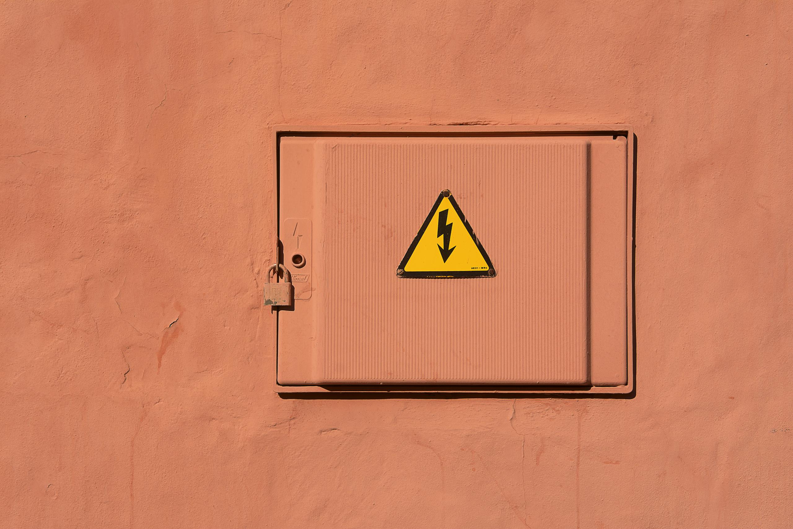 Bright yellow high voltage warning sign on a locked electrical box.